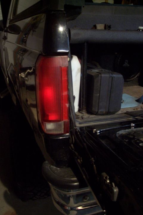 1995 Ford Bronco - Rear view of a black pickup truck, showing the taillight and open tailgate with a toolbox.