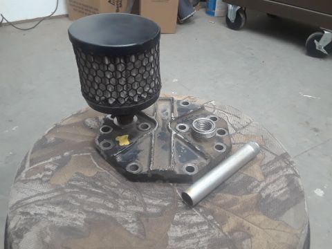 1985 Ford Bronco - An air filter assembly and a metal tube are displayed on a camouflage surface.