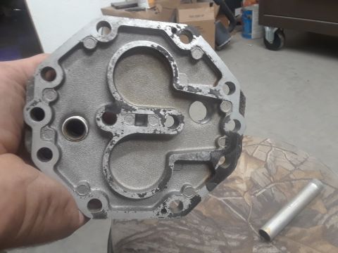 1985 Ford Bronco - A metal component, possibly an engine part, is held up for inspection, revealing its internal structure and mounting points.