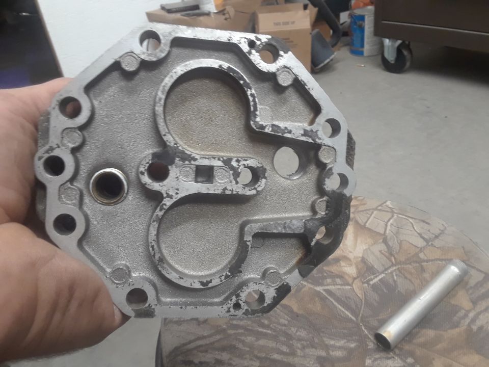 Metal part held in hand, showing circular openings and bolt holes