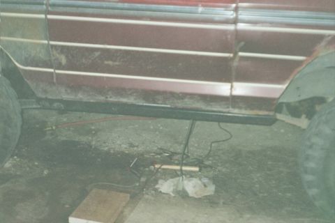 1979 Ford Bronco - Undercarriage of a maroon vehicle with visible rust and attached equipment.