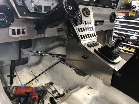 1992 Jeep Wrangler - The interior of a vehicle shows a custom dashboard with a large shifter and multiple switches, along with a drill on the floor.
