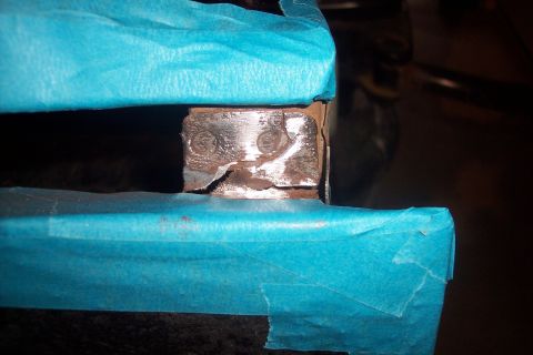 1995 Ford Bronco - A close-up view of a damaged metal bracket, partially covered with blue masking tape.