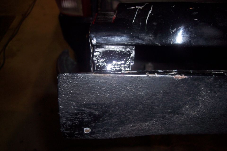 Close-up of a black metal vehicle frame component with a silver bracket attached