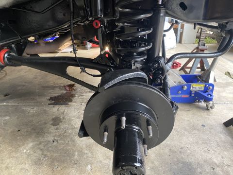 1994 Ford Bronco - A close-up view of the front suspension and braking system of a black Ford Bronco, likely undergoing maintenance or modification. The image…