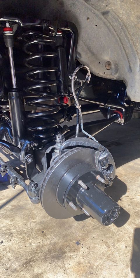 1994 Ford Bronco - A close-up view of the front suspension and braking system of a vehicle, likely a 1994 Ford Bronco, with newly installed black painted comp…