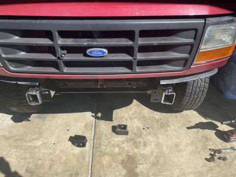 1994 Ford Bronco - Front view of a red Ford Bronco with a black grille and aftermarket hitch receivers mounted on either side of the front bumper. Several hit…