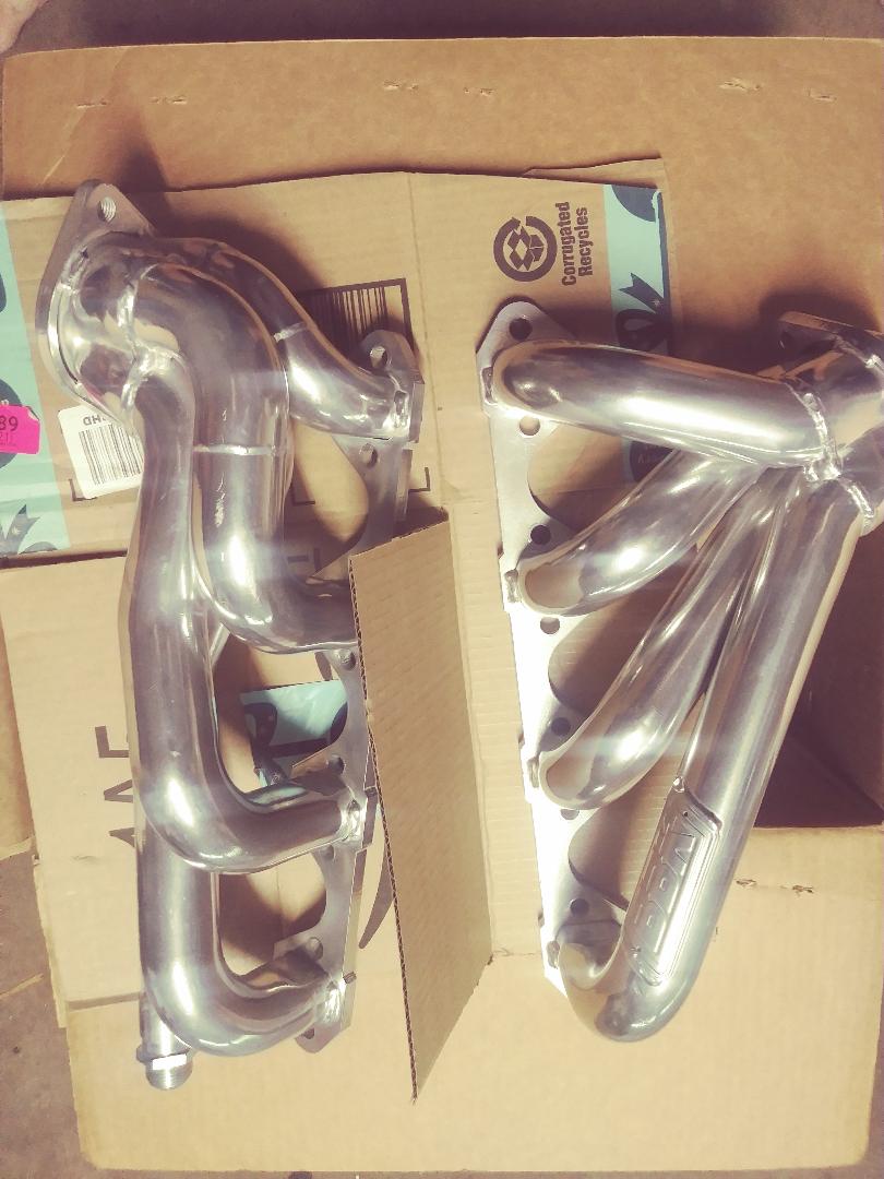 Two chrome exhaust headers on cardboard boxes