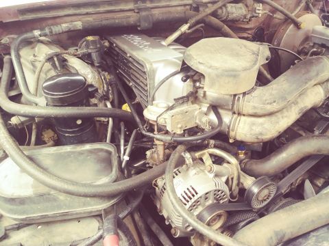 1996 Ford Bronco - Close-up view of the engine bay of a 1996 Ford Bronco, showcasing various components including the intake manifold, alternator, and hoses.