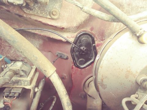 1996 Ford Bronco - A close-up view of the firewall area in a vehicle, showing a black grommet with wires passing through it, a brake booster, and various hose…
