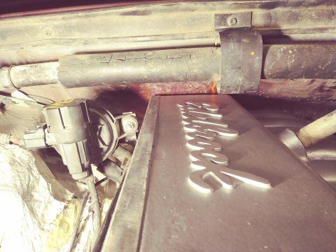 1996 Ford Bronco - A close-up view of the engine bay of a 1996 Ford Bronco, showing a metal valve cover with raised lettering and various engine components in…