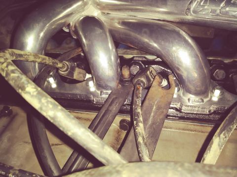 1996 Ford Bronco - Close-up view of polished metal exhaust headers bolted to a black engine block. Various hoses and brackets are visible in the foreground an…