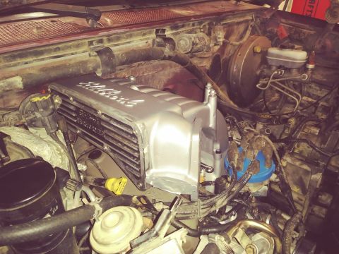 1996 Ford Bronco - The engine bay of a red Ford Bronco shows a newly installed silver Edelbrock intake manifold. Various engine components, wiring, and hoses…