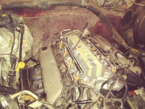 1996 Ford Bronco - The engine bay of a Ford Bronco shows the intake manifold with fuel injectors and wiring harnesses. A silver coolant reservoir with a Ford…