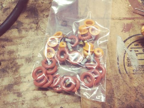 1996 Ford Bronco - A clear plastic bag filled with various small red and orange rubber O-rings and some metal components. The bag is placed on a rough, textur…