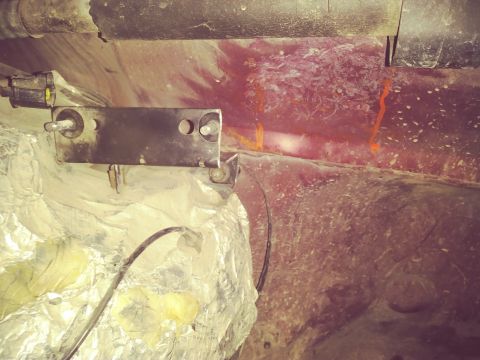 1996 Ford Bronco - A metal bracket is mounted to the underside of a vehicle, possibly for an accessory. Insulation material is visible below the bracket, with…