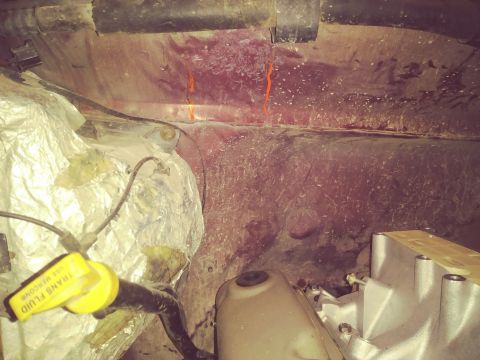 1996 Ford Bronco - The image shows a close-up view of the engine bay of a vehicle, focusing on the firewall area. Two distinct orange lines are visible on the…