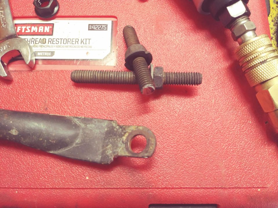 Craftsman thread restorer kit, bolt, and metal bracket on a red surface.