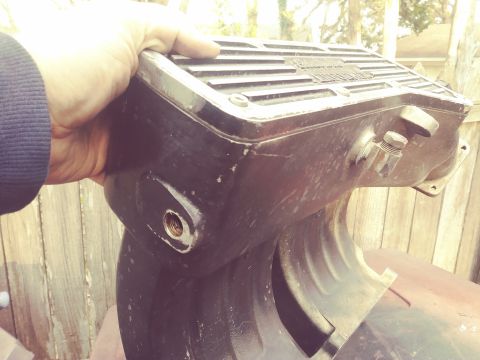 1996 Ford Bronco - A hand holds a black, rectangular automotive part with ribbed texture on top and a threaded fitting on the side. The part is mounted on a r…