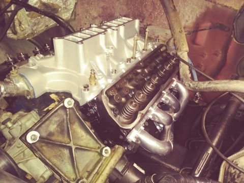 1996 Ford Bronco - A close-up view of a V8 engine with a silver intake manifold and chrome exhaust headers. The engine appears to be in a state of assembly or…