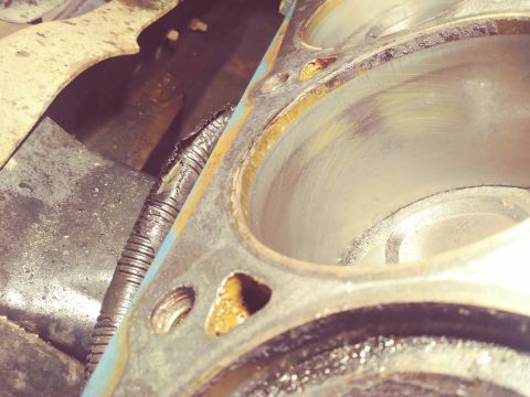 1996 Ford Bronco - Close-up view of the cylinders of a V8 engine block, showing wear marks and some gasket residue. A damaged corrugated hose is visible in th…