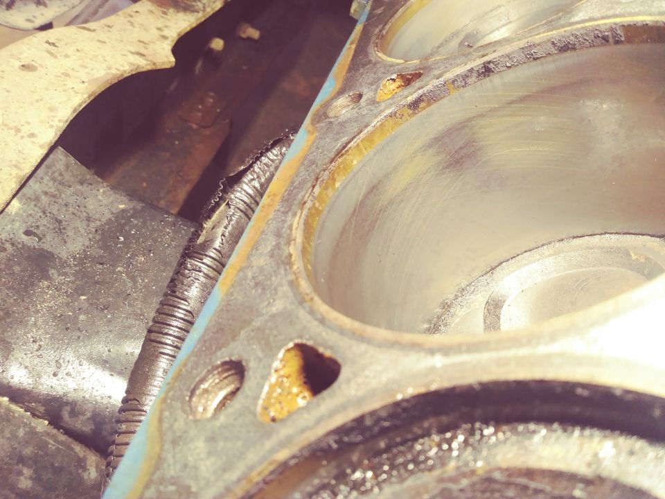 Engine block cylinders with wear marks and a damaged corrugated hose.