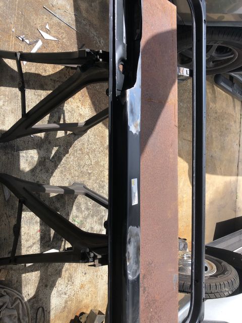 1992 Jeep Wrangler - A close-up, overhead view shows a black metal frame with a large, rusty metal panel attached. The frame appears to be part of a vehicle's c…