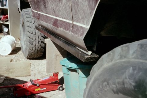 1979 Ford Bronco - The vehicle is supported by a jack and a green bin, with large tires visible.