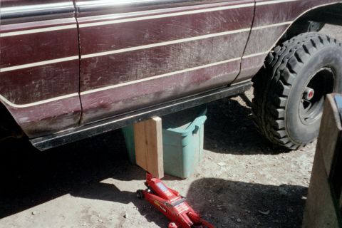 1979 Ford Bronco - A maroon vehicle, possibly a 1978 model, is supported by a jack and bin, revealing its side profile and large tire.