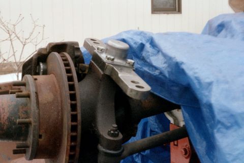 1979 Ford Bronco - Close-up view of a steering linkage component, likely from a truck or SUV, with a rusty brake rotor visible.
