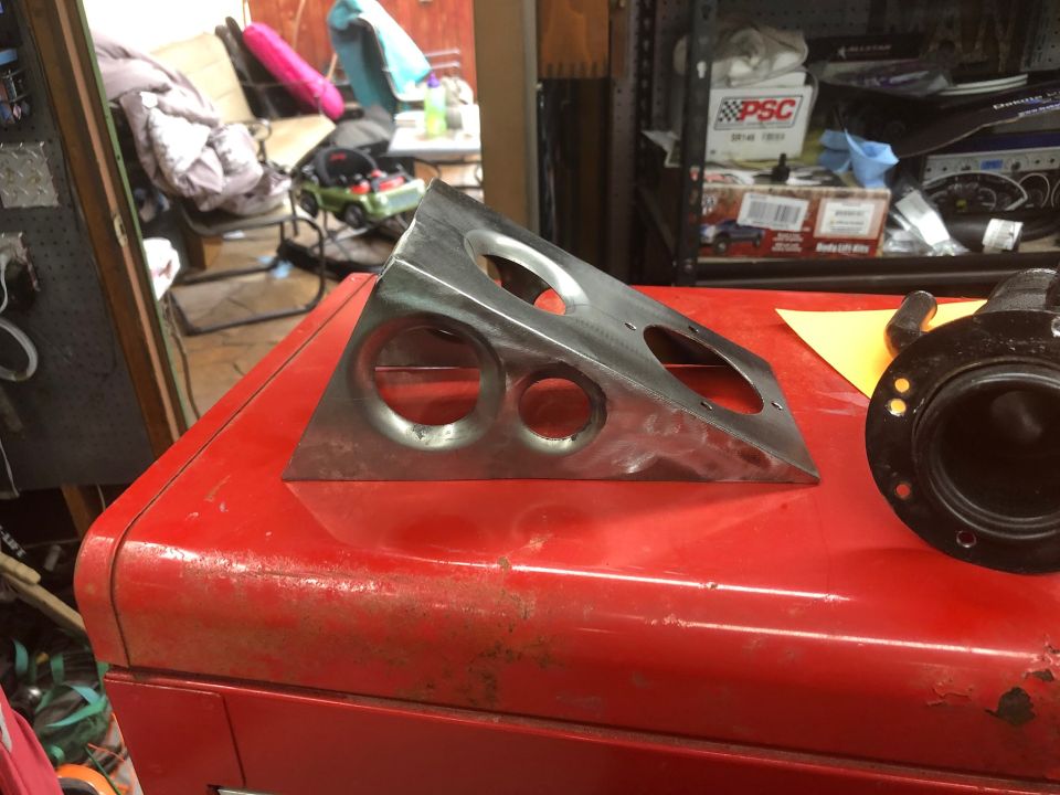 Triangular metal bracket with holes on a red toolbox next to a black circular part.