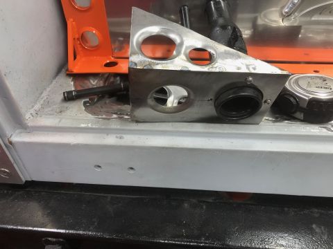 1992 Jeep Wrangler - A close-up view of a custom metal bracket with multiple holes, attached to a vehicle's interior floor. A black rubber grommet is installed…