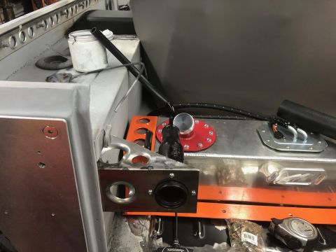 1992 Jeep Wrangler - A close-up view of a custom fuel tank installation in a vehicle, featuring a red fuel cap, a silver sending unit, and black hoses. The tank…