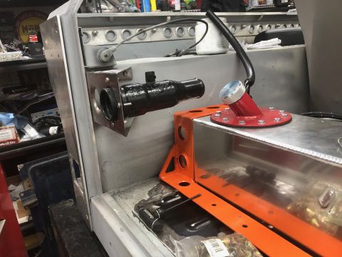 1992 Jeep Wrangler - A close-up view of a custom fuel tank and filler neck assembly being installed in a vehicle. The assembly includes a red fuel filler adapte…
