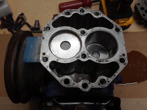1985 Ford Bronco - A close-up view of a disassembled engine component, possibly a cylinder head, with two distinct bores visible. Tools and a power tool are s…