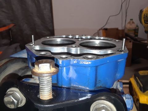 1985 Ford Bronco - A close-up view of a blue engine block with two cylinder bores visible. A large, rusty bolt is fastened to a black mounting bracket below t…