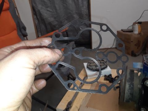 1985 Ford Bronco - A person's hands hold a black gasket with multiple circular cutouts. The gasket appears to be a part for a vehicle, possibly related to an…