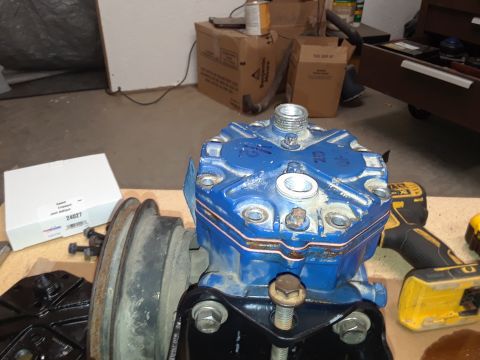 1985 Ford Bronco - A blue compressor head with a pulley attached is mounted on a black bracket. A yellow Dewalt drill and a white box with part number 24027 a…