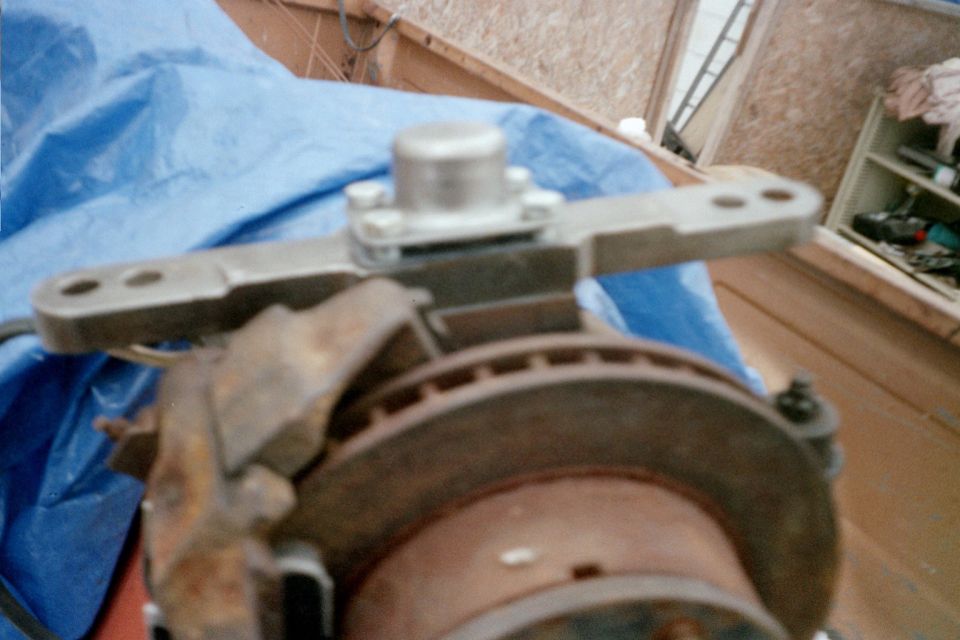 Steering arm assembly attached to a rusty brake rotor and caliper