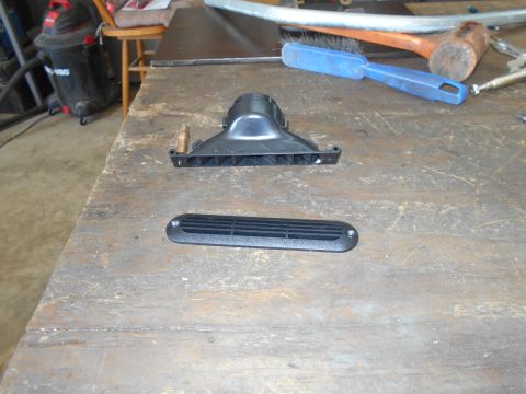 1992 Ford Bronco - A black plastic vent cover and a black plastic air intake component with a copper fitting are displayed on a weathered wooden workbench. To…