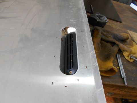 1992 Ford Bronco - A close-up view of a black vent installed in a brushed aluminum panel, possibly part of a vehicle modification. The panel has several small…