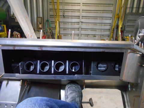 1992 Ford Bronco - Close-up view of the interior of a vehicle's dashboard, showing a section with multiple circular vents and a metallic housing. A person's l…