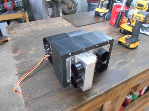 1992 Ford Bronco - A custom-built HVAC unit with four circular vents and wiring is mounted on a wooden workbench. Several DeWalt power tools and spray cans ar…
