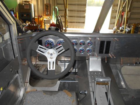 1992 Ford Bronco - The interior of a custom-built vehicle is shown, featuring a metal dashboard with multiple gauges, a steering wheel, and a floor-mounted sh…