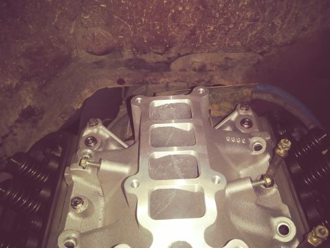 1996 Ford Bronco - A close-up, overhead view of a silver aluminum intake manifold installed on a V8 engine. The manifold has four rectangular intake ports and…