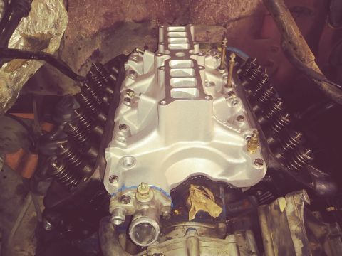 1996 Ford Bronco - A close-up, high-angle view of a V8 engine's intake manifold and valve covers. The silver intake manifold is prominent, with visible bolts…