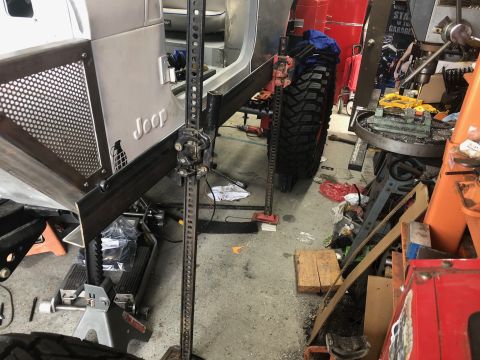 1992 Jeep Wrangler - A custom Jeep Wrangler is being worked on in a garage, with a Hi-Lift jack positioned next to the rear tire and a drill press visible in th…