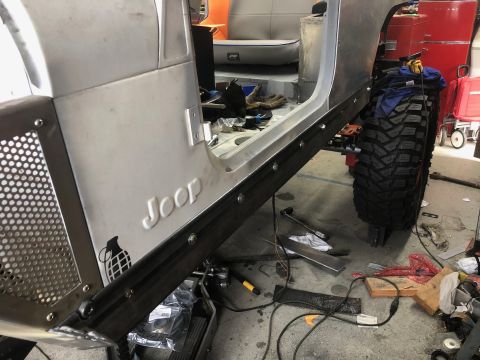 1992 Jeep Wrangler - The side of a partially assembled Jeep Wrangler is shown, featuring the "Jeep" logo embossed on the body, a custom metal rocker panel, and…