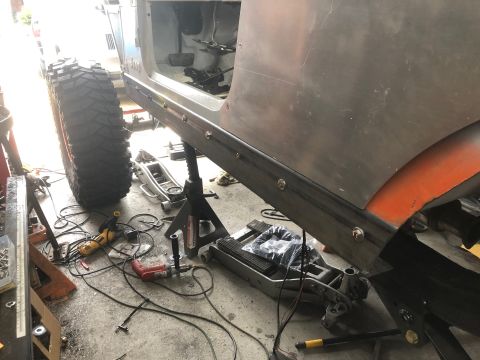 1992 Jeep Wrangler - The side of a Jeep Wrangler is shown being worked on in a garage. A large tire, metal plating, and various tools are visible.