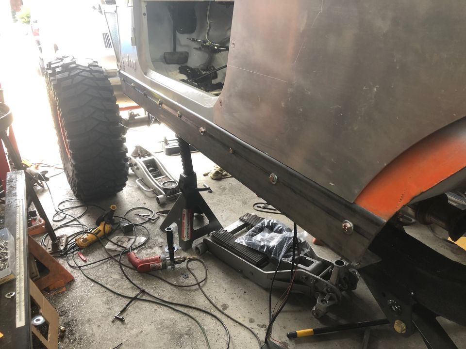 Jeep Wrangler side panel and tire with tools in a garage setting.